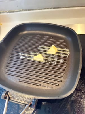 Per friggere la bistecca, è meglio usare una padella in ferro battuto con delle tacche. Il vantaggio principale è che le tacche creano un aroma di bruciato ad alta temperatura, trattenendo al contempo il sugo, rendendo la bistecca bruciacchiata all'esterno e tenera all'interno, con un aspetto e un sapore gradevoli.
Per prima cosa, scalda la padella. Aggiungi il burro e fallo sciogliere.