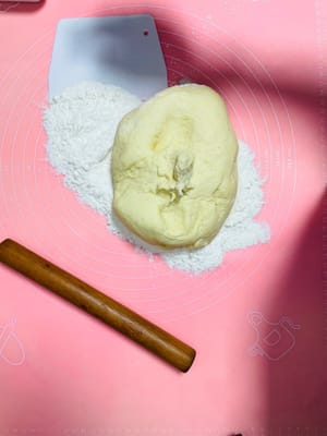 Espolvoree harina uniformemente sobre la superficie de trabajo para evitar que la masa se pegue. Luego, saque con cuidado la masa del cubo y amásela y presione con ambas manos. A medida que la muñeca ejerce fuerza rítmicamente, la masa se compacta gradualmente y los pequeños poros ocultos en su interior desaparecen gradualmente durante el amasado repetido, hasta que la superficie de la masa queda plana y lisa, delicada y elástica.