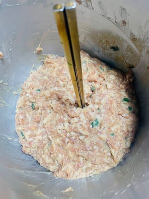 Cuando el relleno de carne esté bien mezclado y adquiera una consistencia firme y pegajosa, ¡es hora de añadir el toque clave del sabor! Primero, vierta el aceite aromático de cebolleta para que su rico aroma penetre en los espacios entre las partículas de carne; luego, vierta el aceite de sésamo suave y, por último, espolvoree con cebollino fresco picado. Remueva rápidamente y uniformemente. Dado que el relleno contiene mucho líquido, se recomienda sellarlo y refrigerarlo durante más de dos horas antes de usarlo. Esto no solo permitirá que el relleno absorba completamente la fragancia, sino que también hará que la textura sea más compacta, no se deshaga fácilmente al envolverlo y el producto final tendrá un sabor más delicioso y firme.