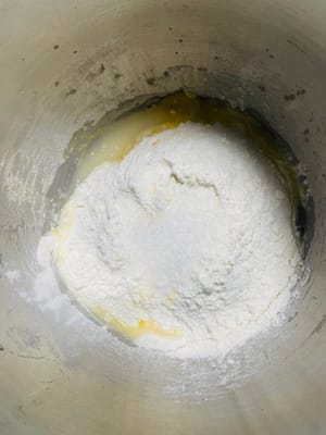 Masukkan air, ragi, 450g tepung (50g untuk adonan nanti), 4g garam, dan 20g gula ke dalam mangkuk pencampur. Uleni hingga adonan menjadi halus dan lembut. Tutup dengan penutup dan biarkan berfermentasi hingga mengembang dua kali lipat.