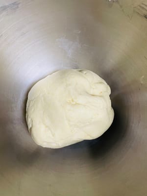 En un bol, añadir agua, levadura, 450 g de harina (50 g para la masa posterior), 4 g de sal y 20 g de azúcar. Amasar hasta obtener una masa suave y fina. Tapar y dejar fermentar hasta que doble su volumen.