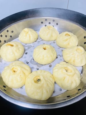 Después de envolver los bollos, colóquelos cuidadosamente en la vaporera, dejando suficiente espacio entre ellos, ya que experimentarán una segunda fermentación y crecerán aproximadamente 1,5 veces su tamaño original. Una vez finalizada la fermentación, puede comenzar a cocinarlos al vapor. Después de que el agua hierva, baje el fuego a medio-alto y cocine al vapor durante 13 minutos. Después de apagar el fuego, no abra la tapa inmediatamente y cocine a fuego lento durante otros 3 minutos para que los bollos cuajen por completo. Finalmente, transfiera los bollos a la rejilla de secado a tiempo para evitar que la base se ablande por la acumulación de humedad, lo que afectaría el sabor.
