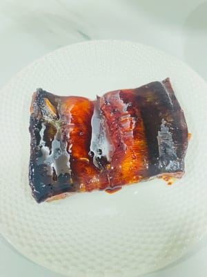 Babi Panggang BBQ: Panaskan oven, olesi loyang dengan minyak, lalu letakkan daging yang sudah dimarinasi di atasnya. Panggang pada suhu 180°C selama 35 menit. (Ini oven Anda sendiri, jadi hati-hati jangan sampai gosong.) Balik oven setiap 15 menit, dan olesi dengan madu selama 5 menit terakhir. Rasanya asin dan gurih, sungguh lezat!
Hei, jangan lihat potongan daging di sebelahnya; itu belut yang saya panggang untuk si kecil. Cium saja aromanya melalui kasa. 😂