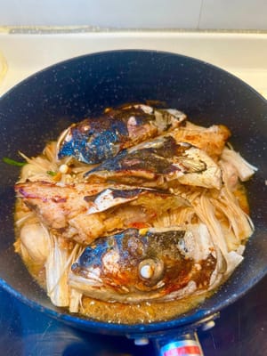 Luego coloque las cabezas de pescado encima de todo, agregue otra cucharada de vino hua tiao para realzar el sabor.