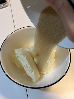 Agregue el azúcar y el queso crema a un tazón grande.