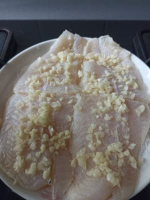 Colocar el filete de panga encima de los fideos y añadir el ajo picado.