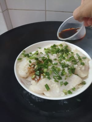Después de 6 minutos, agregue las cebolletas picadas por encima y 2 cucharadas de salsa de soja con mariscos por encima.