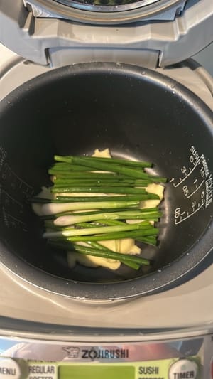 在鍋裡鋪上薑片和蔥花