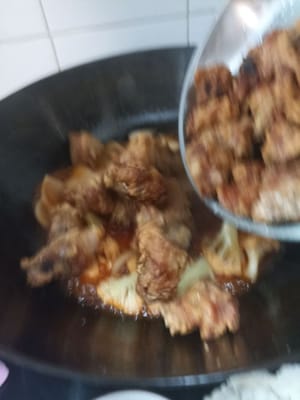 Aggiungere le costine di maiale e continuare a soffriggere finché la salsa non si addensa leggermente.