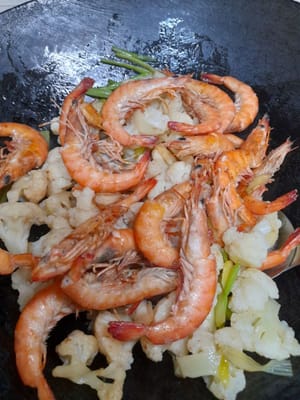 Die Garnelen hinzufügen und kurz kochen, bis die Gewürze gleichmäßig verteilt sind.