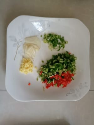 Grüne und rote Paprika, Knoblauch und Ingwer fein hacken. Zwei Frühlingszwiebeln hacken.