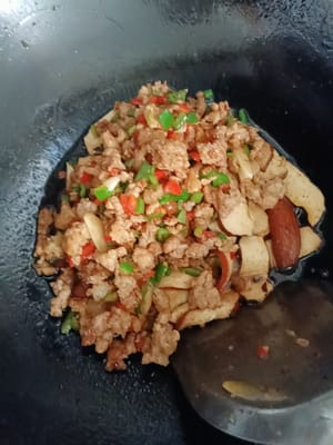 Das Hackfleisch vom Teller in den Topf geben und mit dem getrockneten Tofu anbraten.