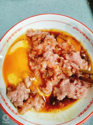 切好的肉末加少許鹽，少許胡椒粉，生抽一茶勺，打入一個土雞蛋，放蔥花一起攪拌均勻
