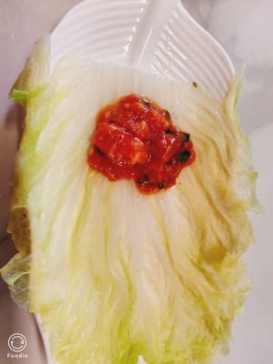調好的肉放在高麗菜上，兩邊對折捲起嚟，擺在盤中。