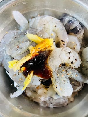 Marinasi udang
Masukkan udang yang sudah ditiriskan ke dalam wadah, tambahkan 1 sendok makan arak masak, 1 sendok makan kecap asin, 1 sendok makan saus tiram, dan sedikit bubuk lada hitam. Kemudian, tambahkan irisan jahe, aduk rata dengan tangan, biarkan udang menyerap bumbu sepenuhnya, lalu marinasi selama lebih dari setengah jam.