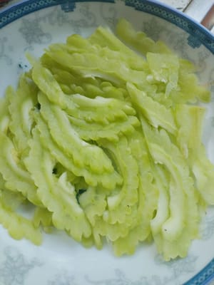 Potong 150 gram pare menjadi irisan.