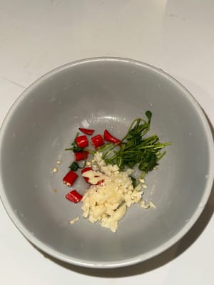將小紅辣椒、香菜和蒜末放入碗中，然後擠入萊姆汁