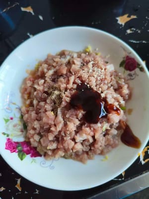 Das zubereitete Hackfleisch mit etwas Salz und Pfeffer würzen. Einen Esslöffel Sojasauce, einen Teelöffel Austernsauce, etwas Zucker und zwei Teelöffel Stärke hinzufügen. Gut umrühren.