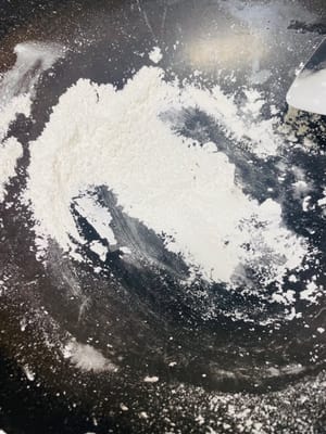 Farina per soffriggere
Mentre la pastella riposa, aggiungete 50 grammi di farina di riso glutinoso nel wok e fate soffriggere lentamente a fuoco basso. Mescolate con una spatola finché l'odore di farina cruda non sarà scomparso e il colore non sarà leggermente giallo. Questa è la farina che userete per evitare che i mooncake si attacchino. Fate attenzione a non bruciarli. Lasciate raffreddare e mettete da parte.