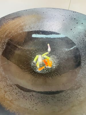 Setelah wajan panas, masukkan minyak goreng dan kecilkan api. Masukkan cabai dan daun bawang, tumis dengan api kecil hingga harum (hati-hati jangan sampai gosong).