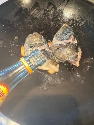 Lavare la testa del pesce e asciugarla. Scaldare la padella, aggiungere l'olio, aggiungere le fette di zenzero e friggere due volte, aggiungere la testa del pesce e friggere entrambi i lati. Rosolare leggermente fino a doratura, aggiungere il vino da cucina per eliminare l'odore di pesce.