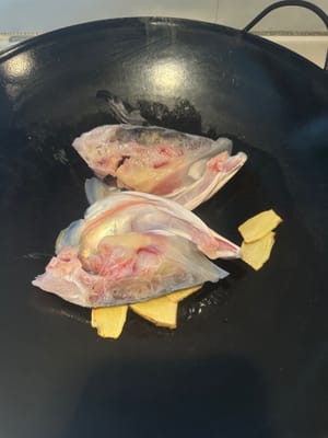 将鱼头清洗干净，擦干水。锅子烧热，放油，放姜片翻煎两下，下鱼头翻煎两面。煎少许金黄色下料酒。去腥味。