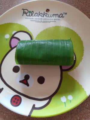 用香蕉葉包裹，然後像這樣捲起嚟。包裹直到麵團用完。