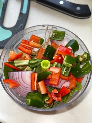 Agregue chiles rojos y verdes, cebolla, raíces de cilantro, hojas de menta y ajo en un molinillo.