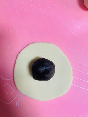 Nehmen Sie ein Stück Teig, rollen Sie es zu einer dünnen Scheibe aus, füllen Sie es mit roter Bohnenpaste, verschließen Sie es mit dem Tigermaul und drücken Sie es dann zum Braten flach.