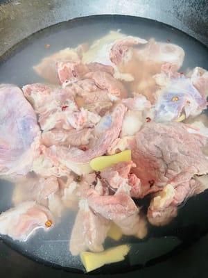 Die Schweineknochen klein schneiden, mit kaltem Wasser abspülen, um oberflächliche Verunreinigungen zu entfernen, kaltes Wasser in den Topf geben, Kochwein, Pfefferkörner (oder Frühlingszwiebeln) und 3 Scheiben Ingwer hinzufügen, bei starker Hitze zum Kochen bringen und 5 Minuten blanchieren, dabei den Schaum abschöpfen, die Schweineknochen herausnehmen, mit warmem Wasser abspülen und abtropfen lassen.