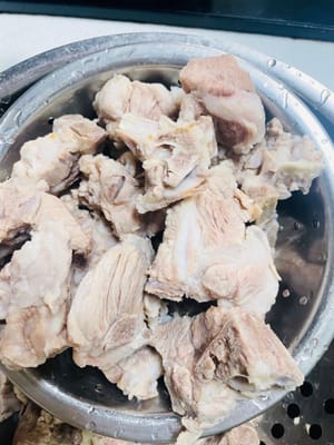 Coupez les os de porc en petits morceaux, rincez à l'eau froide pour éliminer les impuretés de surface, ajoutez de l'eau froide dans la marmite, ajoutez le vin de cuisson, les grains de poivre (ou les oignons nouveaux) et 3 tranches de gingembre, portez à ébullition à feu vif et blanchissez pendant 5 minutes en écumant la mousse, retirez les os de porc, rincez à l'eau tiède et égouttez.
