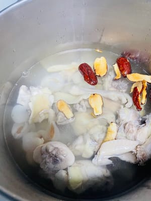 Das verarbeitete Hähnchen, den eingeweichten Ophiopogon japonicus, 10 Litschis (geschält und entkernt), entkernte rote Datteln und Ingwerscheiben in einen Topf geben und zusammen kochen.