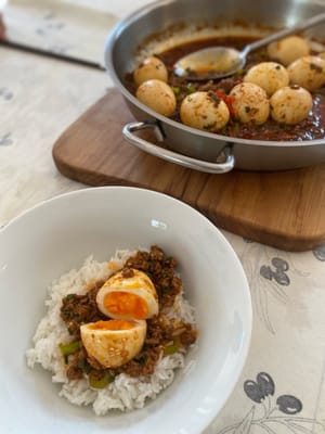 Pour servir, retirer les œufs de la sauce et les disposer sur du riz chaud. Arroser du reste de sauce de la poêle et d'un filet d'huile de sésame. Bon appétit !
