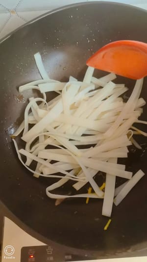 Öl in einem Wok erhitzen, die Reisnudeln hinzufügen und bei mittlerer Hitze einige Sekunden lang unter Rühren anbraten, bis sie weich sind. Etwa sieben bis acht Sekunden braten, dann wenden und vorsichtig mit Essstäbchen auseinanderziehen.