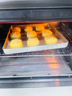6. Baking the Mooncakes
1. Preheat the oven to 200°C. Spray the mooncakes with water before placing them in the oven. Bake them in the middle rack for 5 minutes to set.
2. Remove the mooncakes and wait for the temperature to drop to around 70-80°C. Then, lightly brush the mooncakes with the egg wash you prepared earlier. Be careful not to overdo it, as it will lose the texture. (Use this type of brush, not a silicone one.)
3. Reduce the oven temperature to 160°C. After brushing with the egg wash, return the mooncakes to 160°C and bake for 8-10 minutes. Keep an eye on them to ensure they don't burn.
