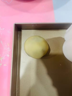 First, sprinkle some dry flour inside the mooncake mold to prevent sticking.
Place the wrapped mooncake balls on a baking sheet, carefully covering them with the mooncake mold. Hold the mold firmly with your hand and press down gently. The beautiful mooncake dough will emerge.