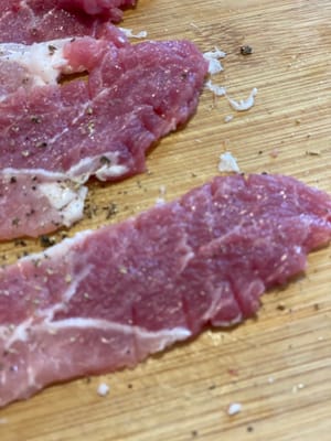 Corte las rodajas de cerdo a lo largo del borde y pinche la superficie para evitar que se enrosquen al cocinarlas.