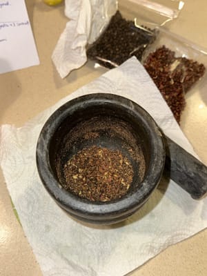 Con un mortero, muele finamente la pimienta negra, la pimienta de Sichuan y la sal.