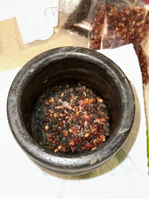À l'aide d'un mortier et d'un pilon, broyer finement le poivre noir, le poivre du Sichuan et le sel