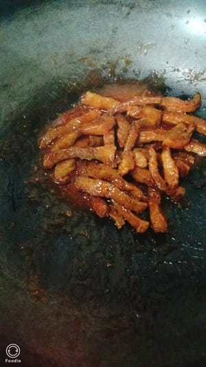 Porter la sauce tomate à ébullition à feu vif. Ajouter les lanières de viande frites et faire revenir plusieurs fois.