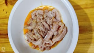 Couper le porc frais en lanières et le mettre dans un saladier. Ajouter une cuillère à soupe de vin de cuisson, du sel et une pincée de poivre. Bien mélanger.