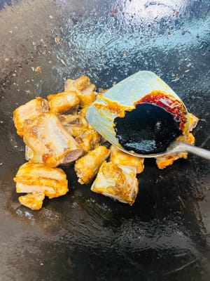 Verser du vin de cuisson sur les bords de la marmite pour parfumer. Ajouter une cuillère à soupe de sauce aux huîtres et une cuillère à soupe de sauce soja foncée pour la saveur et la couleur. (Inutile d’ajouter du sel, car les prunes confites sont salées.)