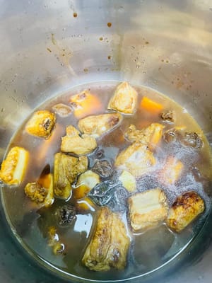 Verser du vin de cuisson sur les parois de la casserole pour rehausser la saveur. Ajouter les tranches de gingembre, l’anis étoilé, les feuilles de laurier, la cannelle, les zestes de mandarine séchés et trempés, les prunes confites et l’eau de cuisson des prunes, puis couvrir d’eau bouillante. Transférer dans un autocuiseur, laisser échapper l’air et cuire 12 minutes. Si vous n’avez pas d’autocuiseur, cuire 40 minutes pour que les épices se mélangent parfaitement aux côtes.