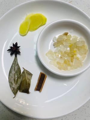 Préparez des tranches de gingembre, des feuilles de laurier, de la cannelle, de l'anis étoilé et du sucre de roche jaune, chacun jouant son rôle pour créer un arôme complexe.