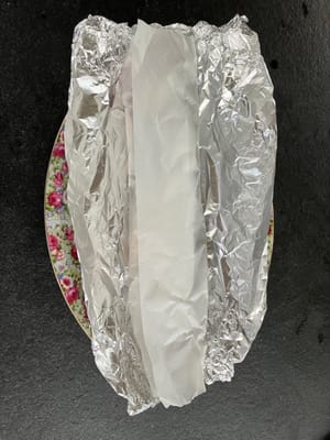 Ponga sal en ambos lados del pescado y envuélvalo con papel pergamino.