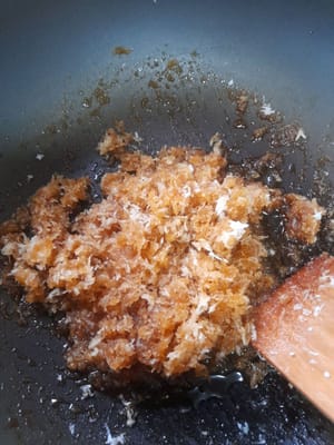 Rimettere l'acqua zuccherata nel Teflon, aggiungere il cocco grattugiato. Cuocere a fuoco medio mescolando finché l'acqua non si riduce e il cocco non si asciuga. Togliere dal fuoco e mettere da parte.