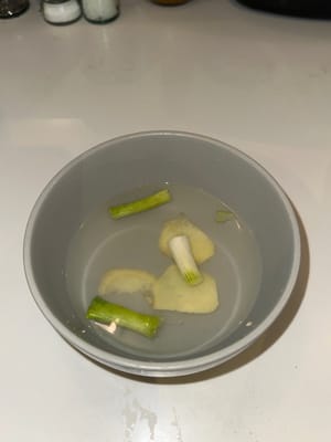 Die Marinade für Rindfleisch zubereiten, indem gehackte Frühlingszwiebeln mit Ingwer in warmem Wasser vermischt werden. 5 Minuten ziehen lassen, damit sich das Aroma entfalten kann.