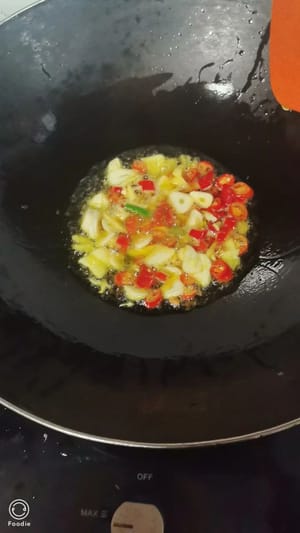 In una pentola a parte, soffriggere zenzero, aglio e peperoncino fino a quando non saranno fragranti. Aggiungere il piccolo pesce di fiume, un cucchiaino di vino da cucina, un po' di peperone verde, un cucchiaino di salsa di soia leggera e mezzo cucchiaino di sale. Saltare in padella fino a quando il tutto sarà ben amalgamato e saporito.