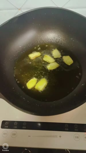 Scaldare l'olio in una padella, cospargere di sale, aggiungere le fette di zenzero, quindi aggiungere i piccoli pesci di fiume e agitare la padella per garantire un riscaldamento uniforme.