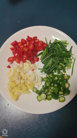 Tagliare i peperoni verdi e rossi a pezzetti, tritare grossolanamente lo zenzero e l'aglio e tagliare l'erba cipollina in lunghi pezzi. Mettere da parte.